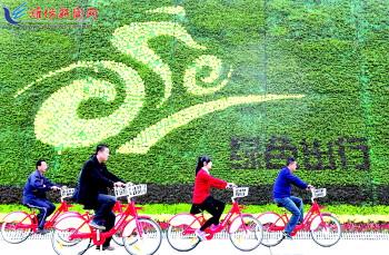 市民騎公共自行車路過市人民廣場一處花壇。記者 張馳